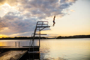 Junge taucht bei Sonnenuntergang in den See - FOLF11965