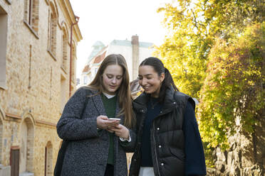 Junge Frauen benutzen ein Smartphone auf einer Straße in der Stadt - FOLF11978
