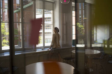 Young woman by window in office break room - FOLF12011