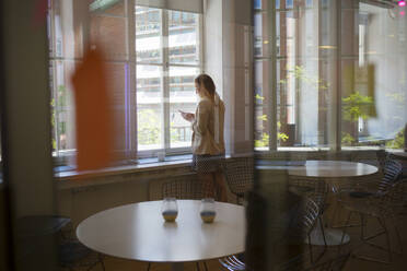 Young woman by window in office break room - FOLF12012