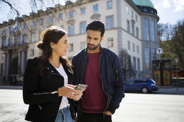 Woman showing man her smartphone on street - FOLF12022