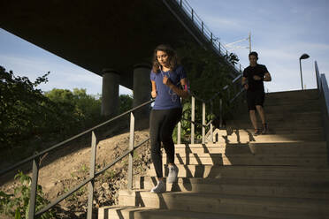 Junge Frau und Mann joggen auf einer Treppe - FOLF12116