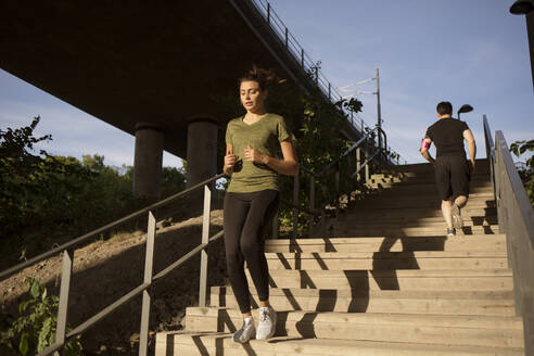 Junge Frau joggt auf Stufen - FOLF12119