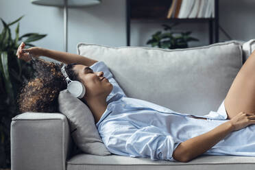 Young woman relaxing on sofa at home - JSRF02346