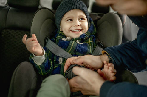 Vater befestigt Sicherheitsgurt im Auto für glücklichen Jungen - ANAF00791