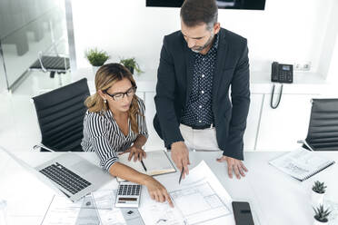 Architekten besprechen am Schreibtisch im Büro eine Strategie über Bauplänen - JSRF02358