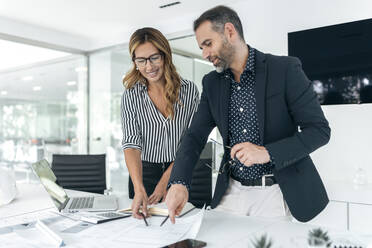 Happy businesswoman and colleague discussing plans in office - JSRF02361