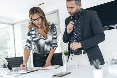 Businesswoman explaining plan to colleague over blueprint - JSRF02362