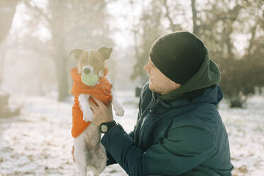 Lächelnder Mann spielt mit seinem Hund im Winter - VSNF00259