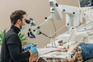 Junge Zahnärztin untersucht die Zähne eines Patienten unter dem Mikroskop in der Klinik - VSNF00272
