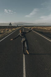 Woman standing on one leg in middle of road - DMGF00909