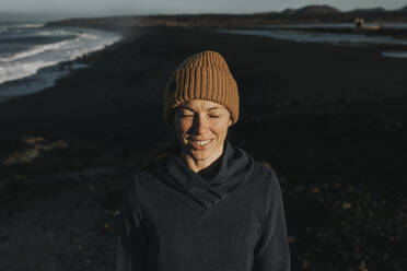 Happy woman with eyes closed standing at Janubio Beach, Lanzarote, Canary Islands, Spain - DMGF00918