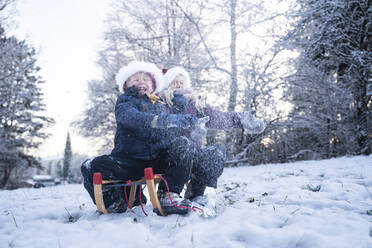 Cheerful boy and girl wearing Santa hats playing in snow - NJAF00171