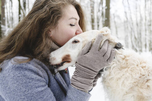 Mature woman stroking and kissing white greyhound dog - EYAF02485