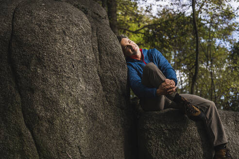 Nachdenklicher Mann lehnt an einem Felsen vor einem Baum - UUF27845