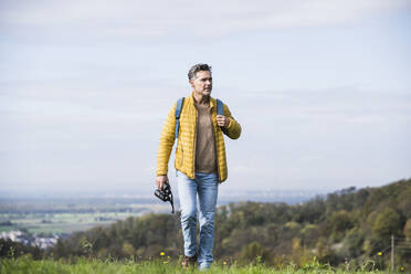 Älterer Mann mit Rucksack und Fernglas beim Wandern im Urlaub - UUF27867