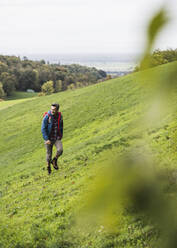 Älterer Mann beim Wandern auf einer Wiese im Urlaub - UUF27890