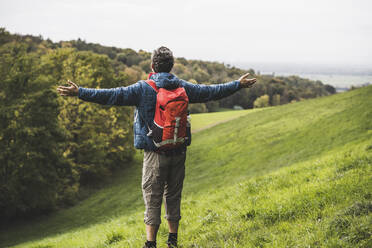 Carefree man with arms outstretched standing under sky - UUF27899