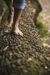 Mature man walking on wooden log - UUF27917