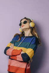 Mädchen hört Musik über Kopfhörer vor lila Hintergrund - VSNF00280