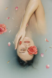 Girl taking bath with roses in bathtub - VSNF00293