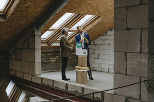 Architekten diskutieren über ein Modellhaus auf einer Baustelle - YTF00395