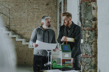 Architect and customer discussing over blueprint at construction site - YTF00455