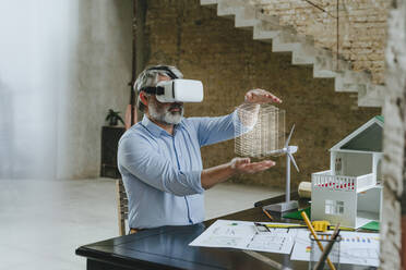 Geschäftsmann mit VR-Brille gestikuliert mit Modellhaus auf dem Schreibtisch auf der Baustelle - YTF00465