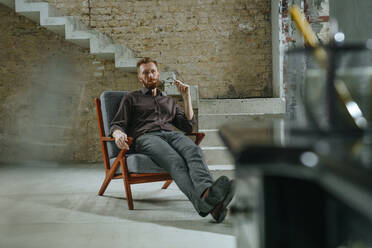 Contemplative businessman sitting in chair at under construction site - YTF00479