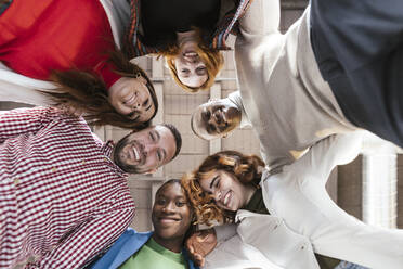 Happy businessmen and businesswomen huddling together in office - LJF02437