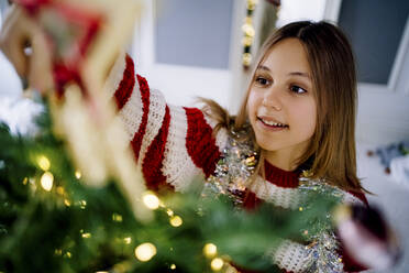 Mädchen schmückt Weihnachtsbaum zu Hause - MDOF00487