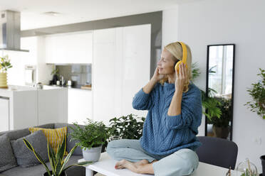 Frau mit drahtlosen Kopfhörern, die zu Hause Musik hört - TYF00597