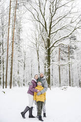 Glückliche Familie umarmt sich im Schnee im Winterpark - EYAF02501