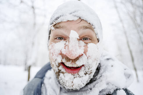 Glücklicher Mann mit schneebedecktem Gesicht im Winterpark - EYAF02506