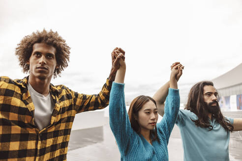 Multirassische Aktivisten, die sich an den Händen halten und miteinander stehen - JCCMF08623