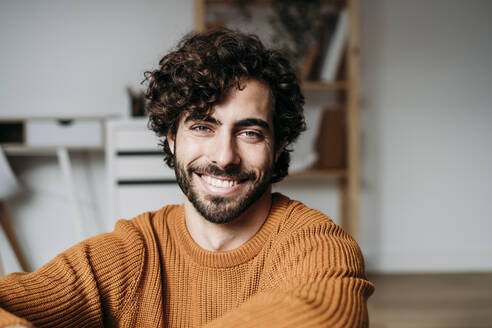 Happy young man sitting at home - EBBF07477