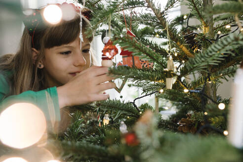 Mädchen schmückt Weihnachtsbaum zu Hause - TYF00629