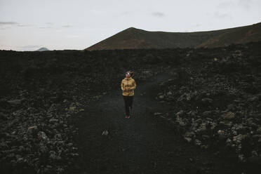 Frau läuft auf einem Weg in der Vulkanlandschaft Caldera Blanca, Lanzarote, Kanarische Inseln, Spanien - DMGF00945