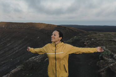 Happy woman with arms outstretched at Caldera Blanca volcano, Lanzarote, Canary Islands, Spain - DMGF00951