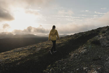 Frau beim Wandern auf einem Berg bei Sonnenaufgang, Vulkan Caldera Blanca, Lanzarote, Kanarische Inseln, Spanien - DMGF00954