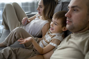 Mother and father with son watching TV at home - ANAF00801