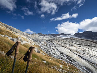 France, Auvergne-Rhone-Alpes, Mountainous landscape of Vanoise National Park with hiking poles standing in foreground - LAF02798