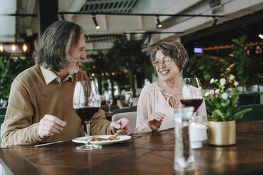 Älterer Mann und Frau sitzen am Tisch mit Weinglas in einem Café - YTF00504