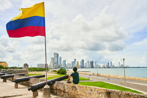 Man sitting by Colombian flag on wall, Cartagena de Indias, Colombia - KIJF04509