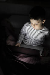 Junge sieht sich zu Hause einen Film auf dem Laptop an - LJF02449