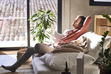 Thoughtful man sitting on sofa in living room - VEGF06142