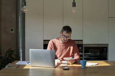 Man examining and calculating financial bills on desk at home - VEGF06165