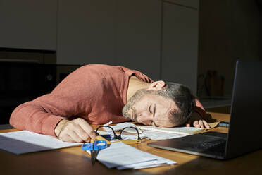 Tired man sleeping on desk with documents and laptop - VEGF06171