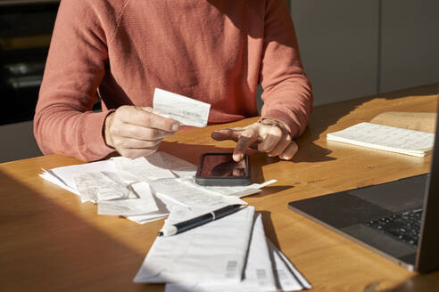 Hands of man with financial bills calculating on smart phone at desk - VEGF06180