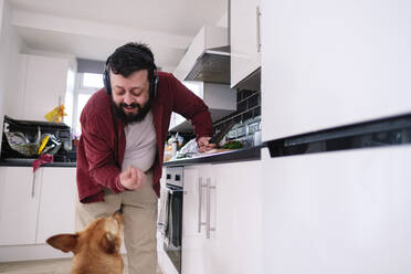 Mature man giving food to dog in kitchen at home - ASGF03228